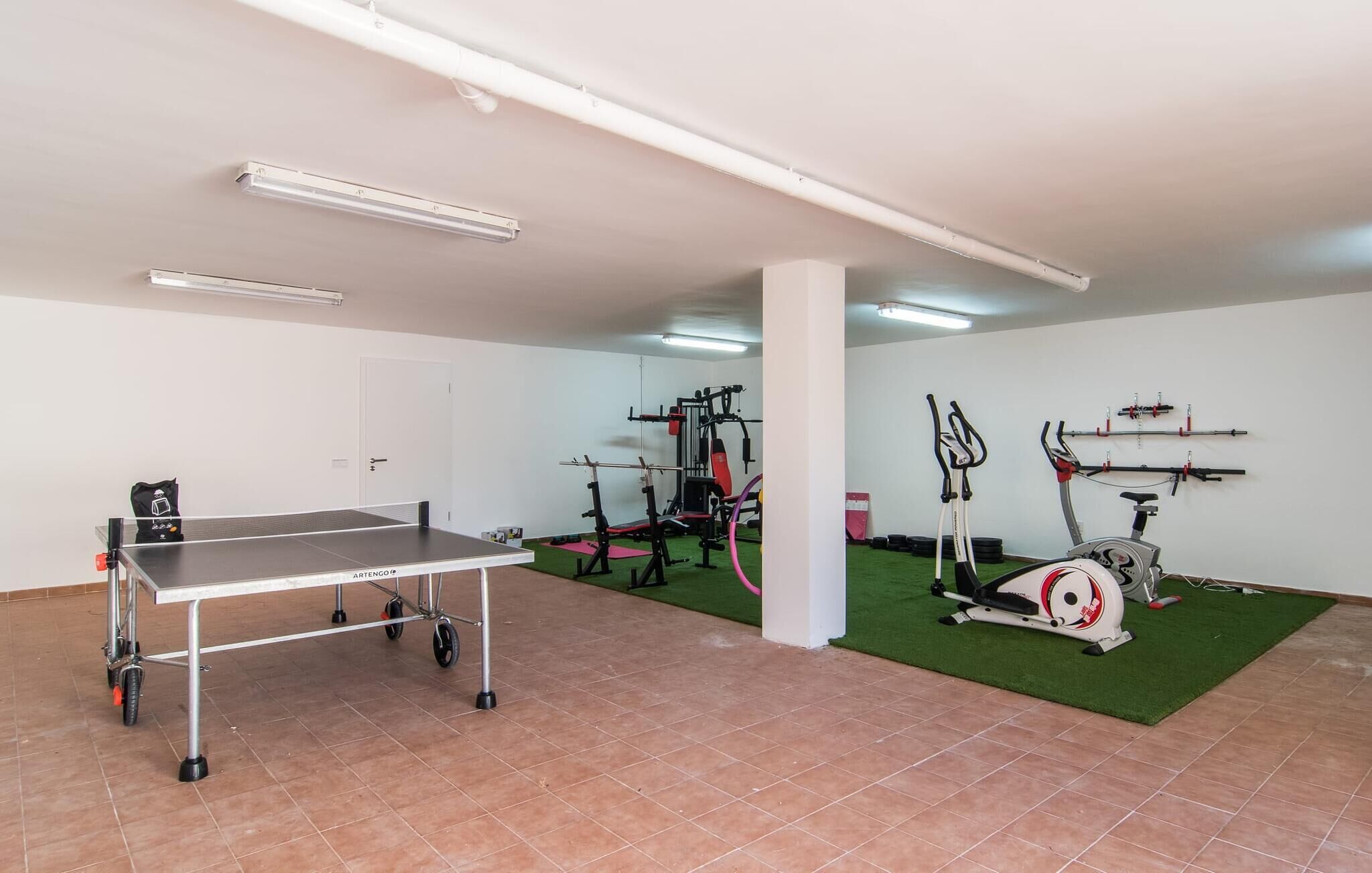 Une salle de sport équipée d’une table de ping-pong, de matériel d’exercice et d’un vélo d’appartement.