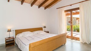 A bedroom with a wooden bed, white bedding, two bedside lamps, and a view of a garden through a sliding glass door. - Lovely home in Arta with private swimming pool, can be inside or outside (Arta)