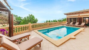 Ein Poolbereich mit Liegestühlen und Meerblick.