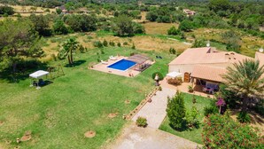 Ein Wohnhaus mit Pool, Terrassenmöbeln und Garten.