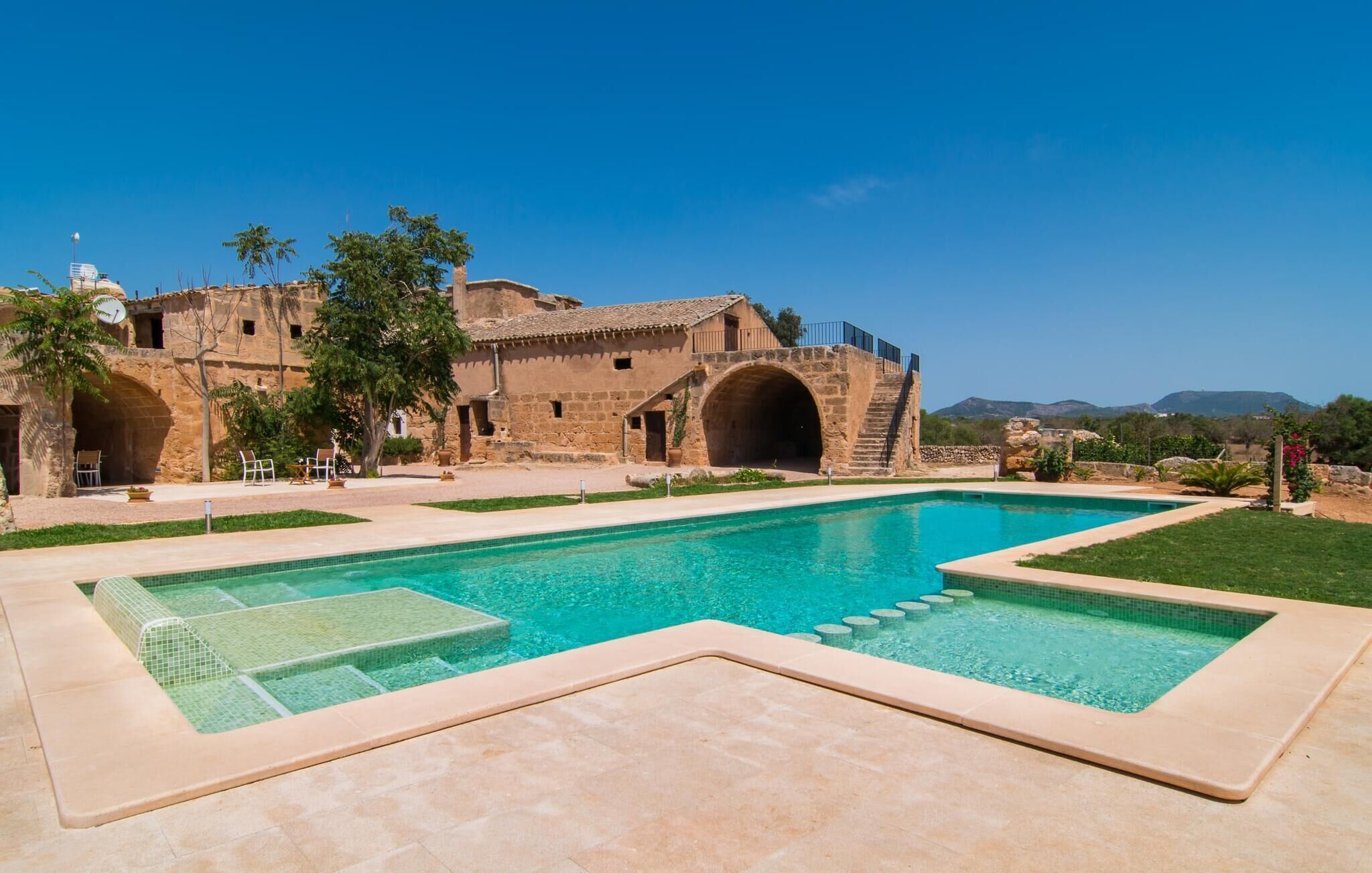 Un espace piscine avec un bâtiment en pierre en arrière-plan.