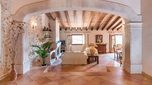 Un'ampia zona giorno con parete in pietra, soffitto in legno e un'ampia arcata.