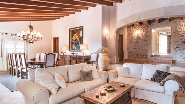 Un soggiorno ampio con soffitto alto, zona pranzo e parete in pietra.