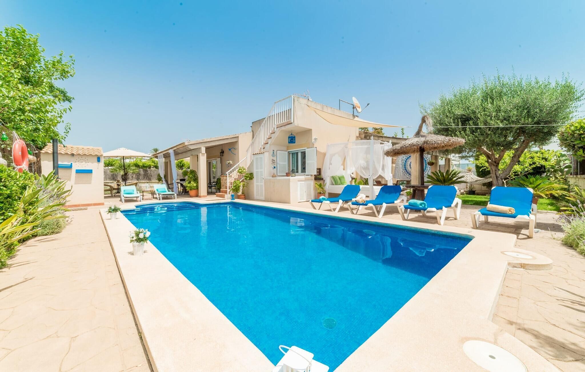 Ein Swimmingpool mit Liegestühlen, einer überdachten Lounge und einem Gebäude mit Treppe.