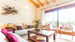 A living room with a sofa, a coffee table with a chess set, a plant, and a view of the outdoors through large windows. - Stunning home in Inca with private swimming pool, can be inside or outside (Inca)