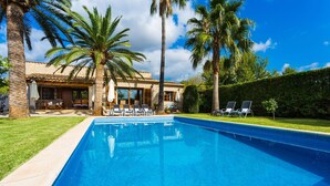 A swimming pool with lounge chairs and palm trees, surrounded by a stone building with a tiled roof. - Stunning home in Inca with private swimming pool, can be inside or outside (Inca)