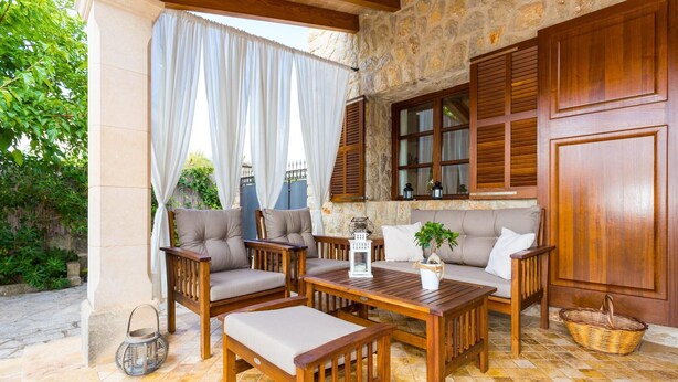A cozy outdoor seating area with wooden furniture, stone walls, and a view of greenery. - Stunning home in Inca with private swimming pool, can be inside or outside (Inca)