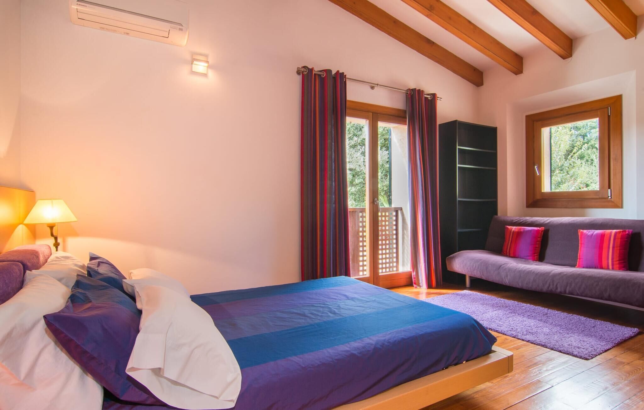 Ein Schlafzimmer mit Bett, Sofa, Fenster und Kleiderschrank.
