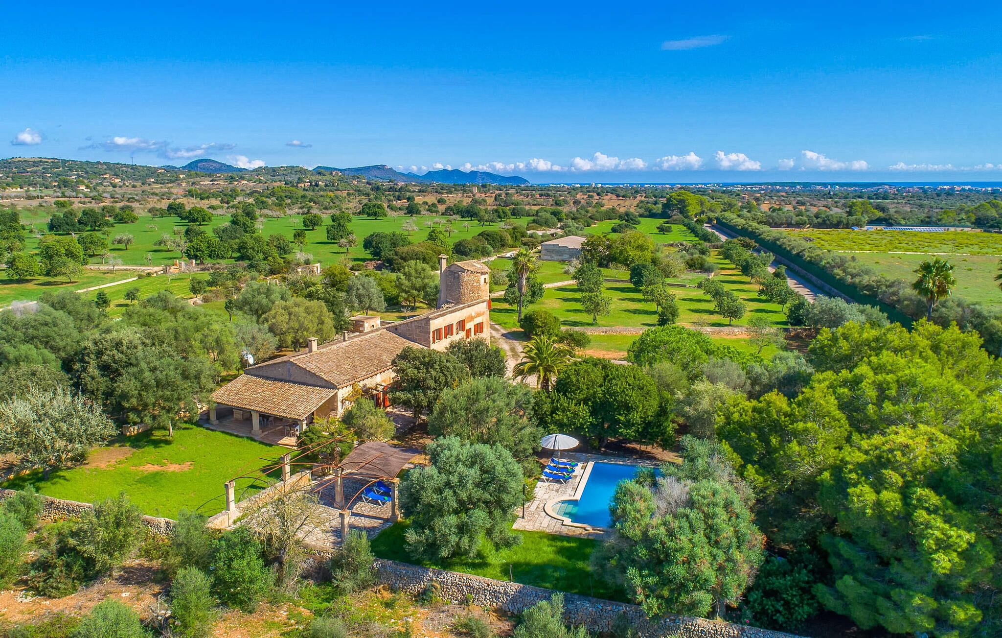 A large estate with a swimming pool, lush greenery, and a view of distant mountains.