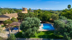 A villa with a swimming pool, surrounded by lush greenery and a view of distant mountains. - Awesome home in Porto Cristo (Porto Cristo)