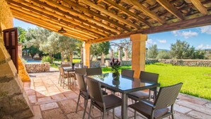 An outdoor patio with a pergola, stone flooring, and a table with chairs. - Awesome home in Porto Cristo (Porto Cristo)