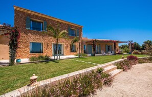 A two-story stone house with a covered patio and a well-maintained lawn. - Stunning home in Ses Salines (Ses Salines)