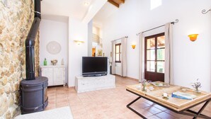 A spacious living area with a fireplace, a television, and a dining table. - Ca Na Castell Son Rubi (Selva)