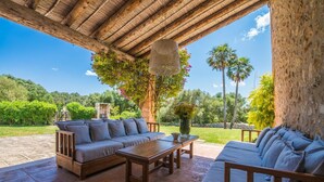 Een buitenmeubilairgedeelte met een houten pergola, een bank, een tafel en een stoel.
