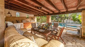An outdoor patio with a dining table, chairs, and a sofa. There is a pool in the background. - Pet friendly home in Galilea (Galilea)