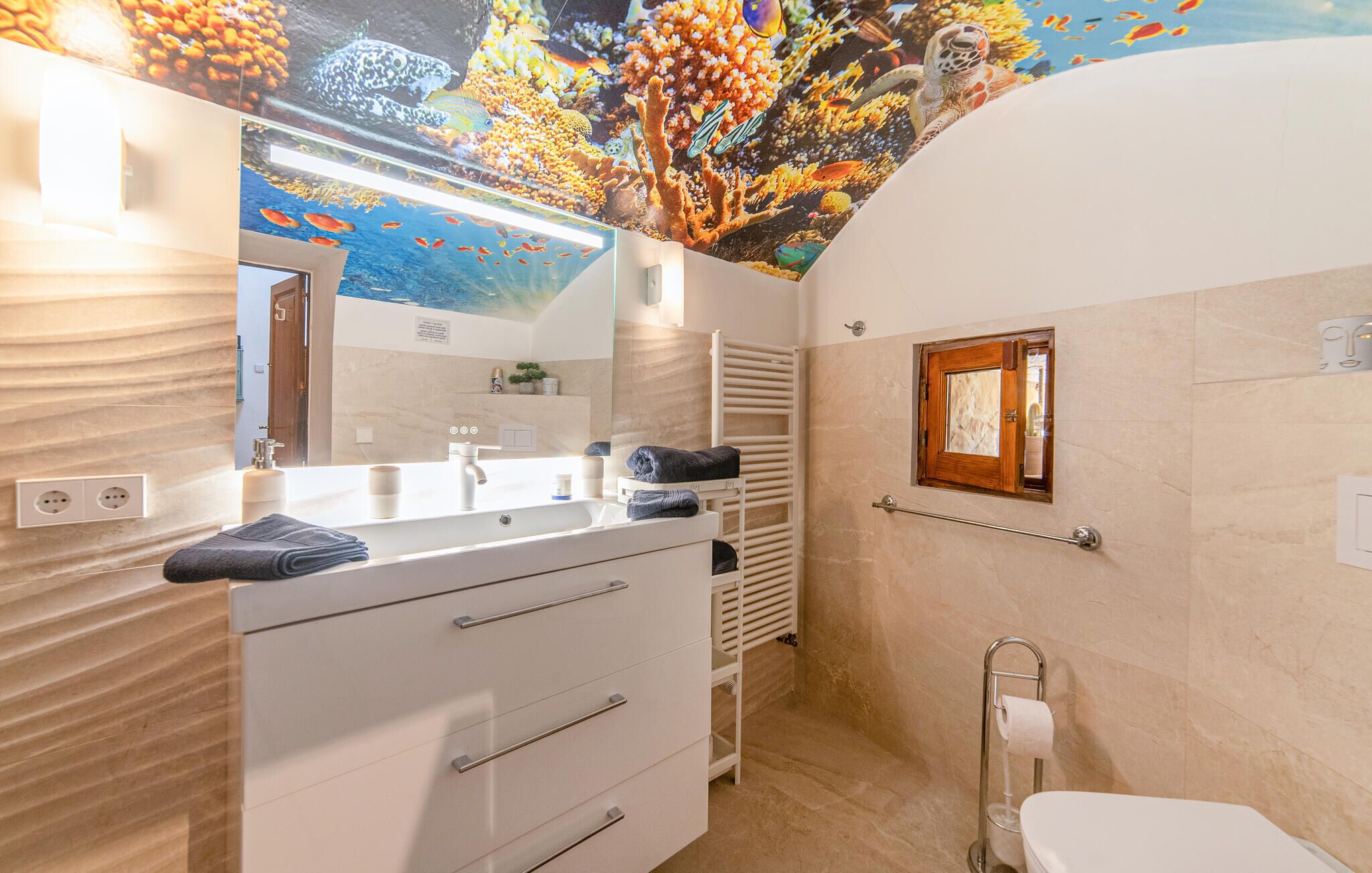 A bathroom with a large mirror, a sink, a toilet, and a towel rack.