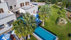 Eine moderne Villa mit Swimmingpool, mehreren Balkonen und üppiger Bepflanzung.