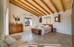 A bedroom with a wooden ceiling, a bed, a nightstand, a dresser, and a window with a view of the outdoors. - Gorgeous home in Son Servera (Son Servera)