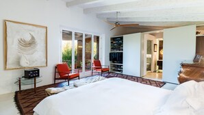 A bedroom with a large bed, two red chairs, a glass coffee table, a ceiling fan, and a sliding door leading to a bathroom. - Nice home in Manacor with sauna (Manacor)