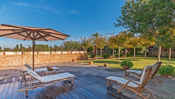 An outdoor deck with wooden lounge chairs and a large umbrella. - Nice home in Manacor with sauna (Manacor)