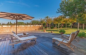 An outdoor deck with wooden lounge chairs and a large umbrella. - Nice home in Manacor with sauna (Manacor)