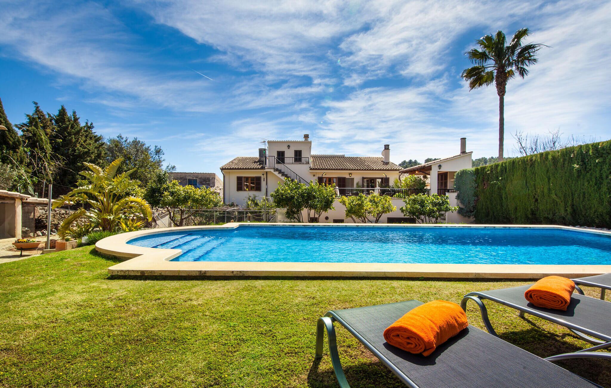 A swimming pool with lounge chairs and a neatly trimmed lawn.