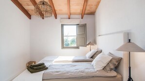 Ein Schlafzimmer mit Bett, Fenster, Lampe und Deckenleuchte.