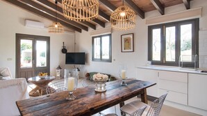 Eine moderne Küche mit Holztisch, Pendelleuchten und einem großen Fenster.