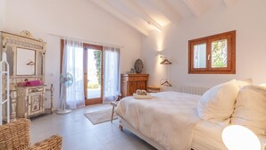 Une chambre à coucher avec un lit, une commode, un miroir, une fenêtre et une porte.