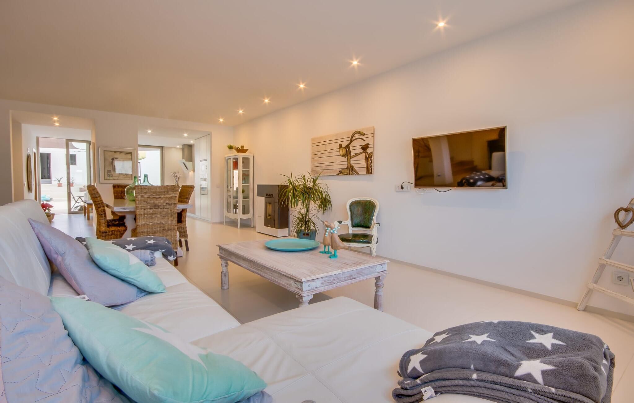 Een gezellige woonkamer met een bank, een salontafel en een televisie aan de muur.