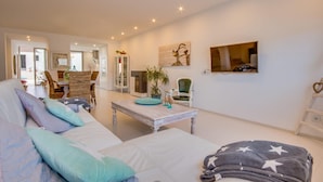 A cozy living room with a sofa, a coffee table, and a TV mounted on the wall. - Lovely home in Muro with private swimming pool, can be inside or outside (Muro)