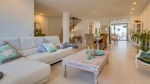 A spacious living room with a white sofa, a wooden coffee table, and a dining area with wicker chairs. - Lovely home in Muro with private swimming pool, can be inside or outside (Muro)