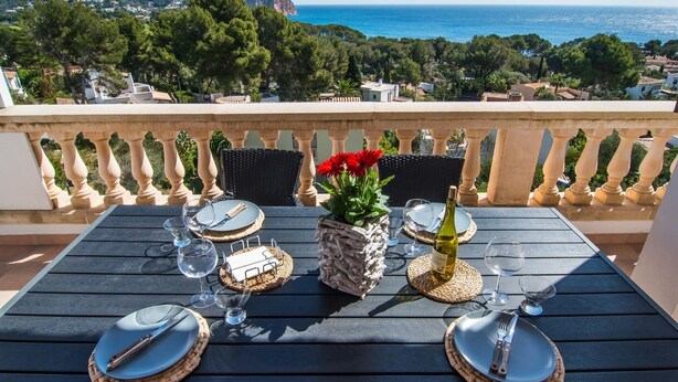 Ein Tisch für zwei Personen mit Blick auf das Meer und die Hügel im Hintergrund.