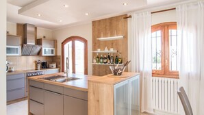Eine moderne Küche mit einer zentralen Kochinsel, eingebauten Geräten und einer Wand mit Holzverkleidung.