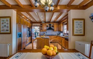 A kitchen with wooden cabinets, a central island, and a fruit bowl on the table. - Stunning home in Cala dOr with private swimming pool, can be inside or outside (Cala dOr)