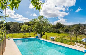 Une piscine entourée d’une clôture en bois, avec un banc et une table avec des chaises.