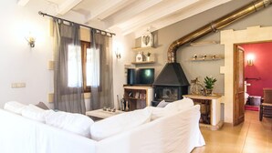 A living room with a white sofa, a television, a fireplace, and a red wall.