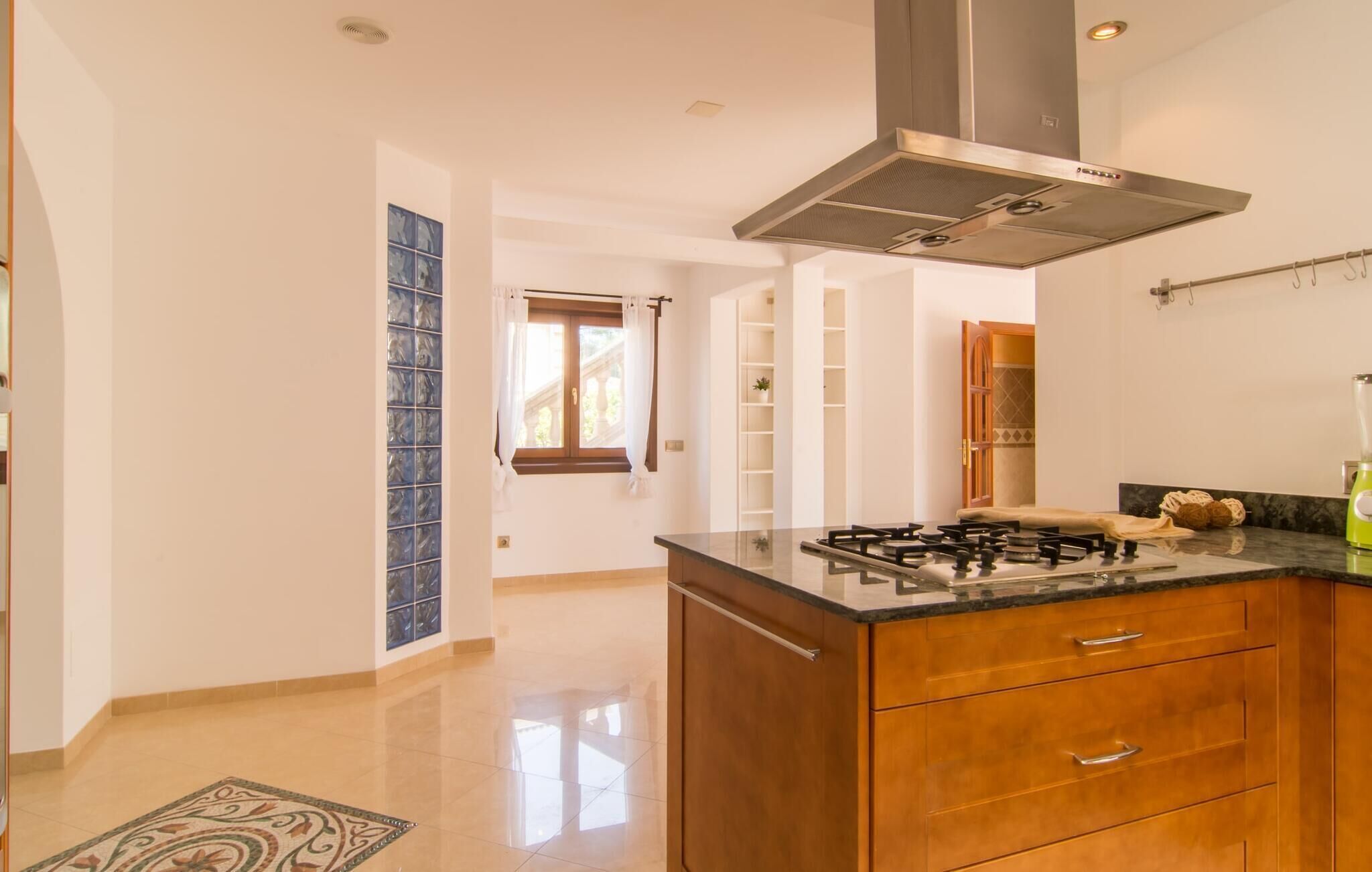 Une cuisine moderne équipée d’une cuisinière à gaz, de meubles en bois et d’une hotte en acier inoxydable.