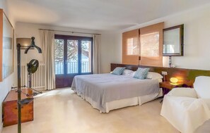 A bedroom with a bed, a nightstand, a lamp, a chair, and a view of the outdoors. - Awesome home in Cala Ratjada (Cala Ratjada)