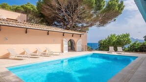 A swimming pool with lounge chairs, a covered seating area, and a view of the sea. - Awesome home in Cala Ratjada (Cala Ratjada)