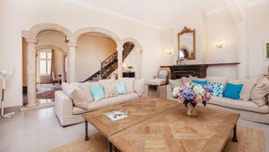 A spacious living room with a large wooden coffee table, two sofas with patterned cushions, a fireplace, and a staircase leading to another level. - La Casa de las Vistas (Palma)