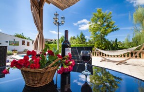 Une table avec une bouteille de vin, un verre de vin et un panier de roses rouges.