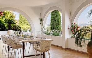 An outdoor dining area with a table set for four, surrounded by white chairs with a lattice design. - Nice home in Pollenca with private swimming pool, can be inside or outside (Pollenca)