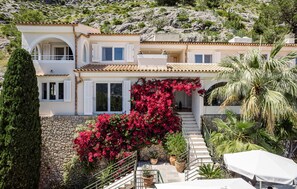 A two-story house with a stone facade, white shutters, and a balcony. - Nice home in Pollenca with private swimming pool, can be inside or outside (Pollenca)