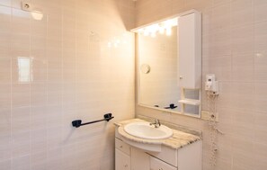 Ein Badezimmer mit weißem Waschbecken, einem Spiegel und einem Handtuchhalter.