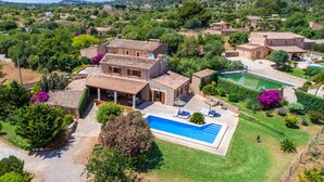 Una amplia villa con piscina, rodeada de exuberante vegetación y un paisaje montañoso.