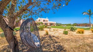 Una casa moderna con un patio amplio, una silla colgante y una zona de piscina.