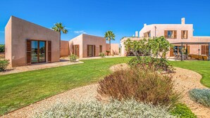 Una casa moderna con varias habitaciones, un césped bien cuidado y un jardín.