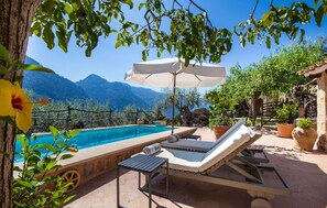 A pool area with lounge chairs and an umbrella, surrounded by greenery and mountains in the background. - Amazing home in Fornalutx with private swimming pool, can be inside or outside (Fornalutx)