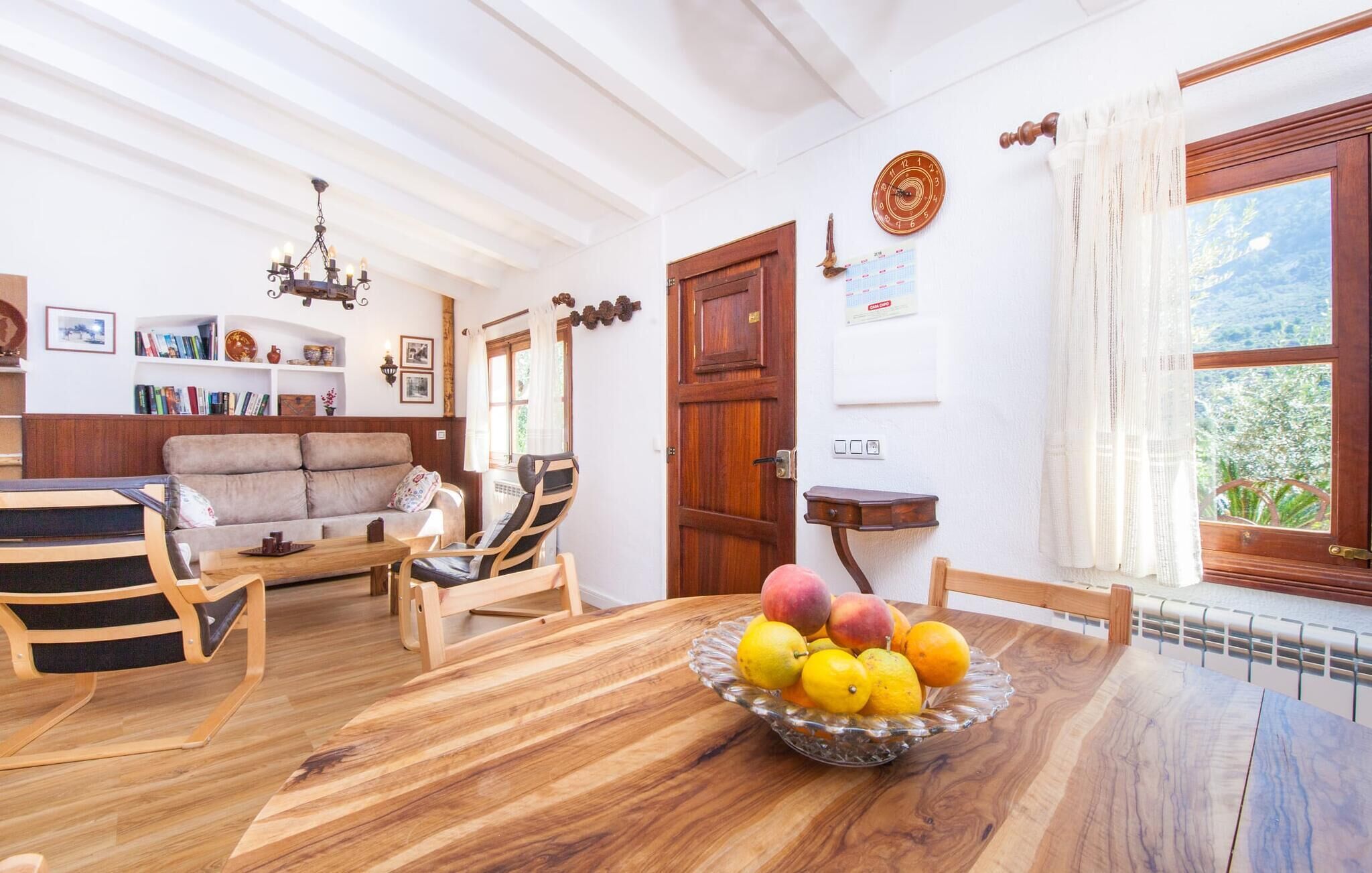 Un salon chaleureux avec une table en bois, un canapé et un coin repas agrémenté d’un panier de fruits.